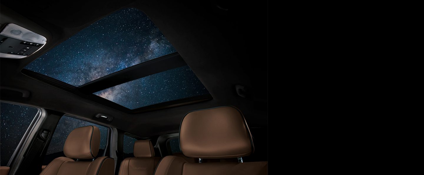 Interior view at night of the opened dual-pane power sunroof on the 2020 Jeep Grand Cherokee Summit.