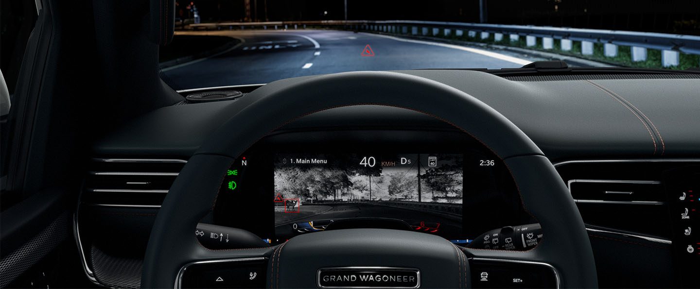 The driver information cluster display in the 2023 Grand Wagoneer Series III, displaying a night vision view of the road ahead with potential obstacles highlighted in red.